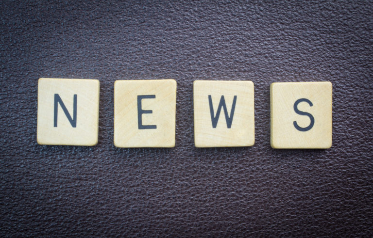 Auf einer Lederoberfläche liegen Scrabble-Buchstaben, die das Wort News bilden.
